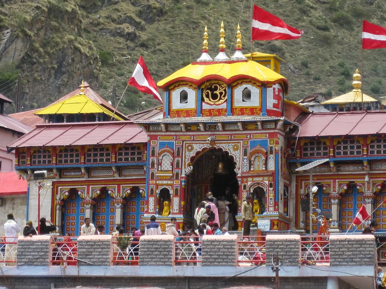 The brightly painted entrance of Badrinath Temple with devotees in the courtyard